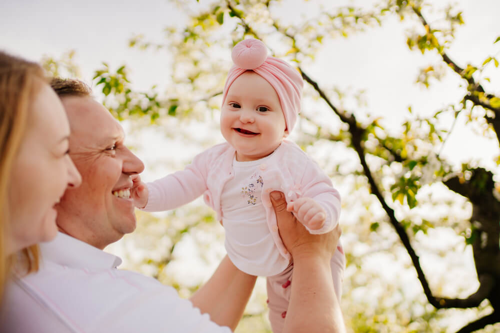 Mom, Dad and Daughter. Family Happiness. A Family With a Baby Daughter in the Spring Flowering Garden.