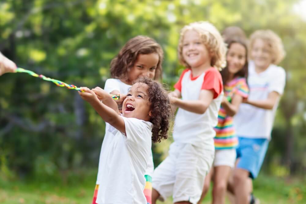 Kids Play Tug of War in Sunny Park Summer Outdoor Fun Activity.