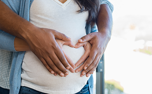 Parents hands holding a heart on the belly