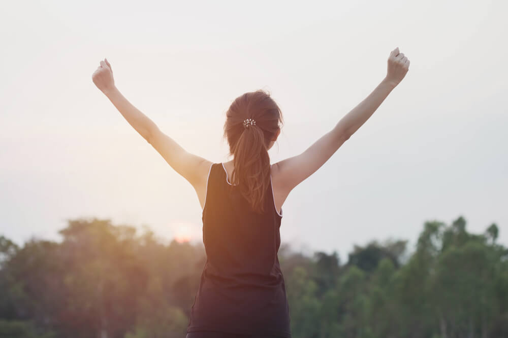 Silhouette of Woman With Hands Raised in the Sunset, Open Arms at Sunrise.
