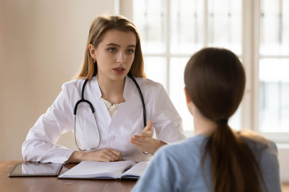 Young Lady Client Patient Visiting Pleasant Attentive Female Doctor Physician at Modern Clinic Medical Center, Listening to Detailed Recommendations of Qualified Specialist