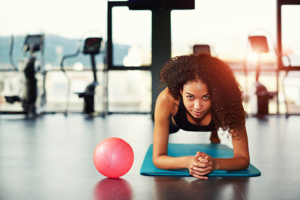 Attractive Young Woman Leaning on Her Elbows Doing Exercise for Buttocks Muscles at Gym