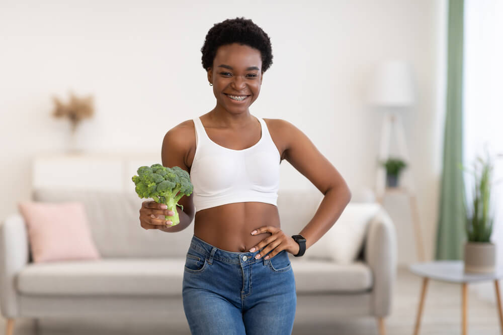 Smiling Skinny African Woman Posing With Broccoli Standing at Home