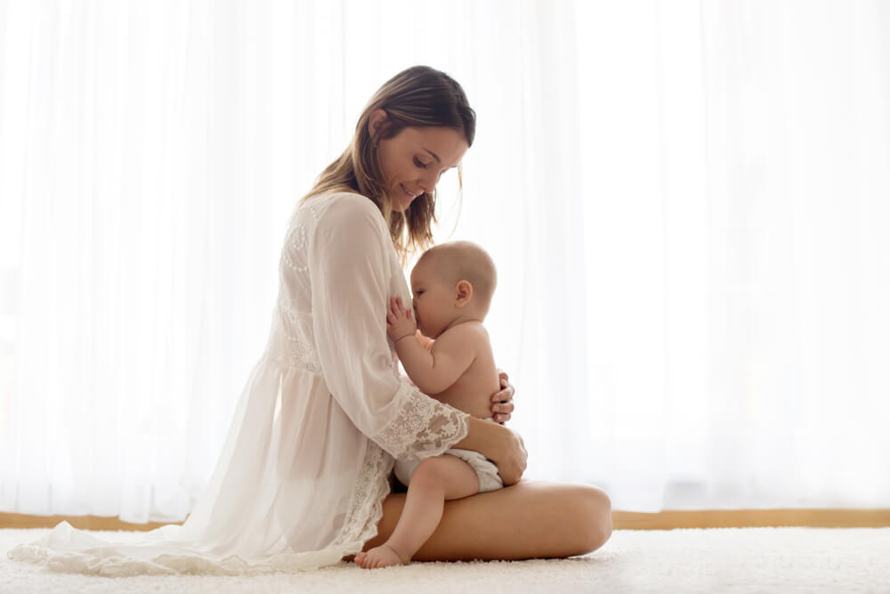 Young Mother Breastfeeding Her Newborn Baby Boy at Home