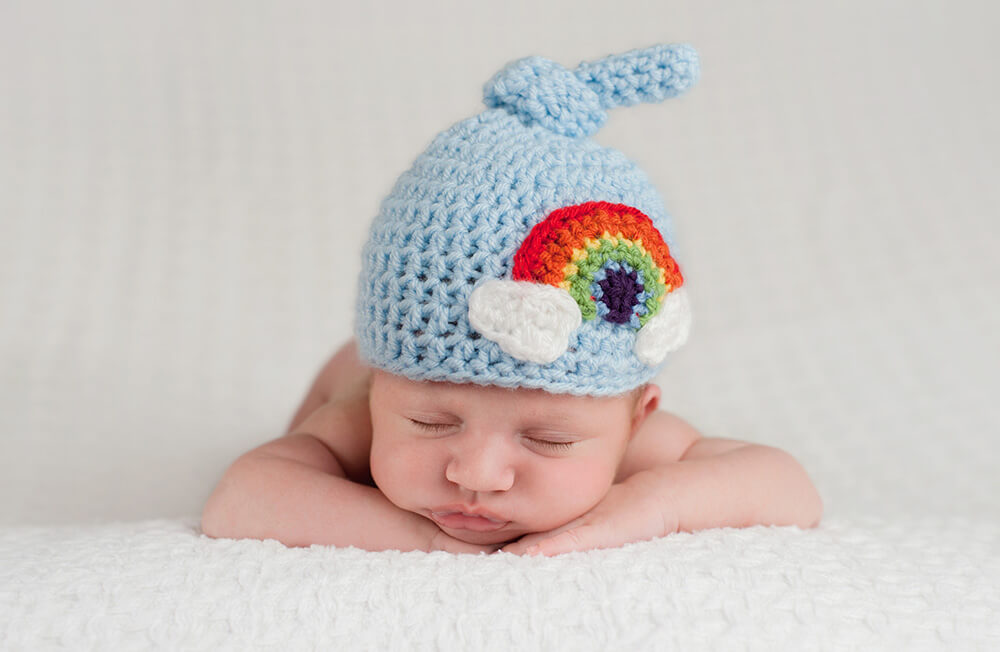 A Baby With a Cap With a Rainbow on It