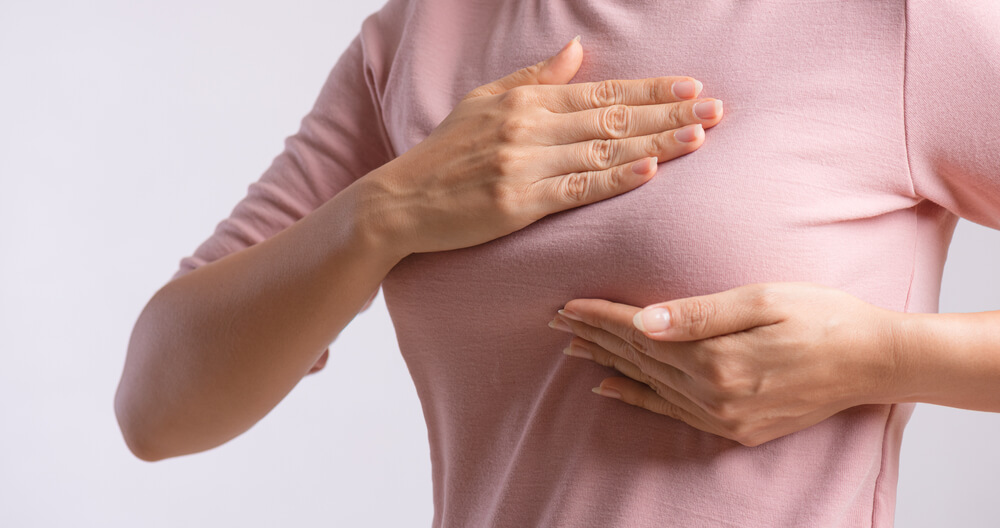 Woman Hand Checking Lumps on Her Breast for Signs of Breast Cancer