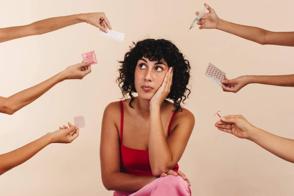 Thoughtful Young Woman and Hands With Different Means of Contraception