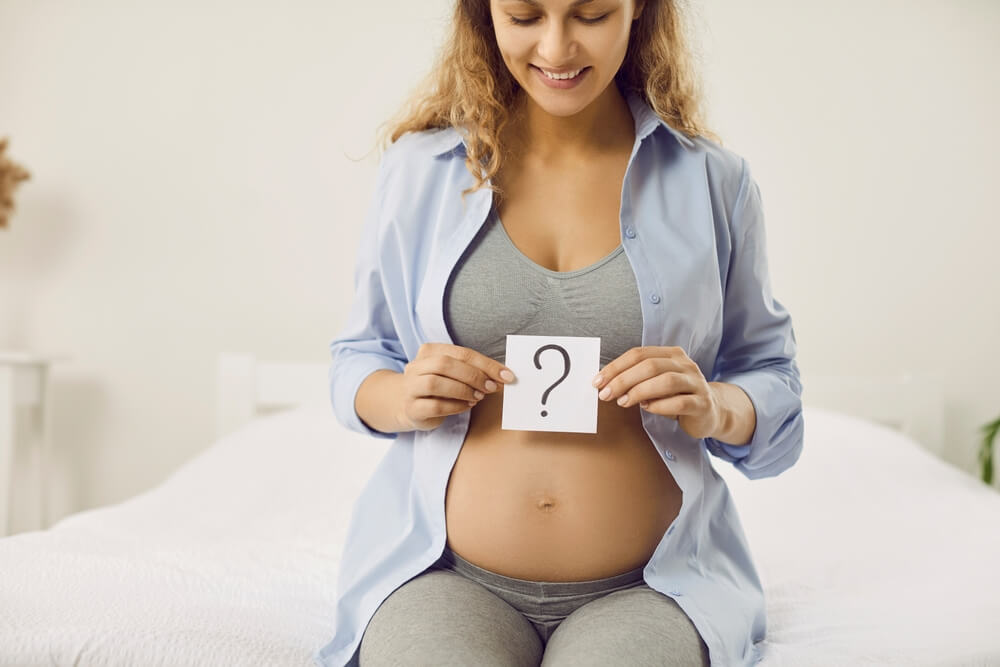 Smiling pregnant lady trying to guess gender of unborn baby.