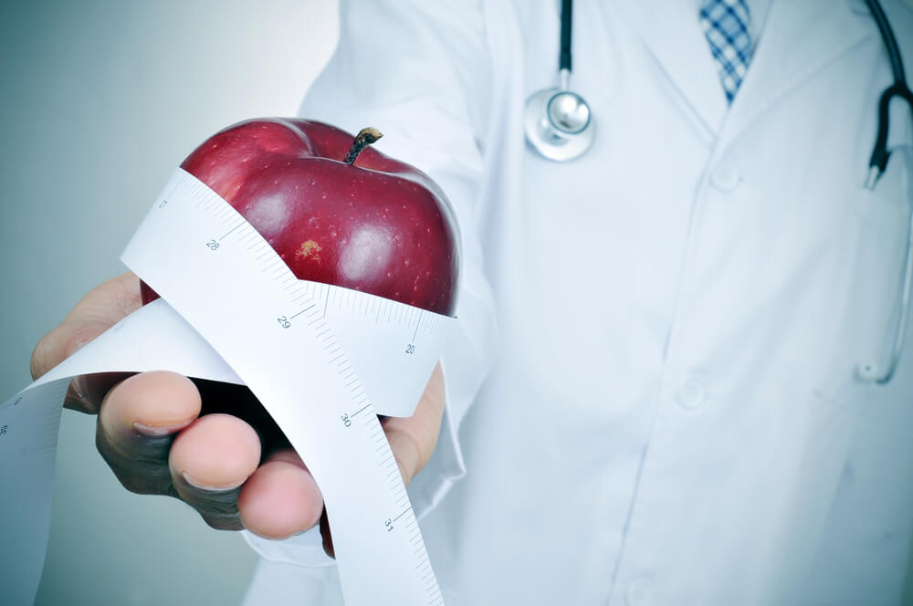 Doctor With a Red Apple and a Measuring Tape in His Hand