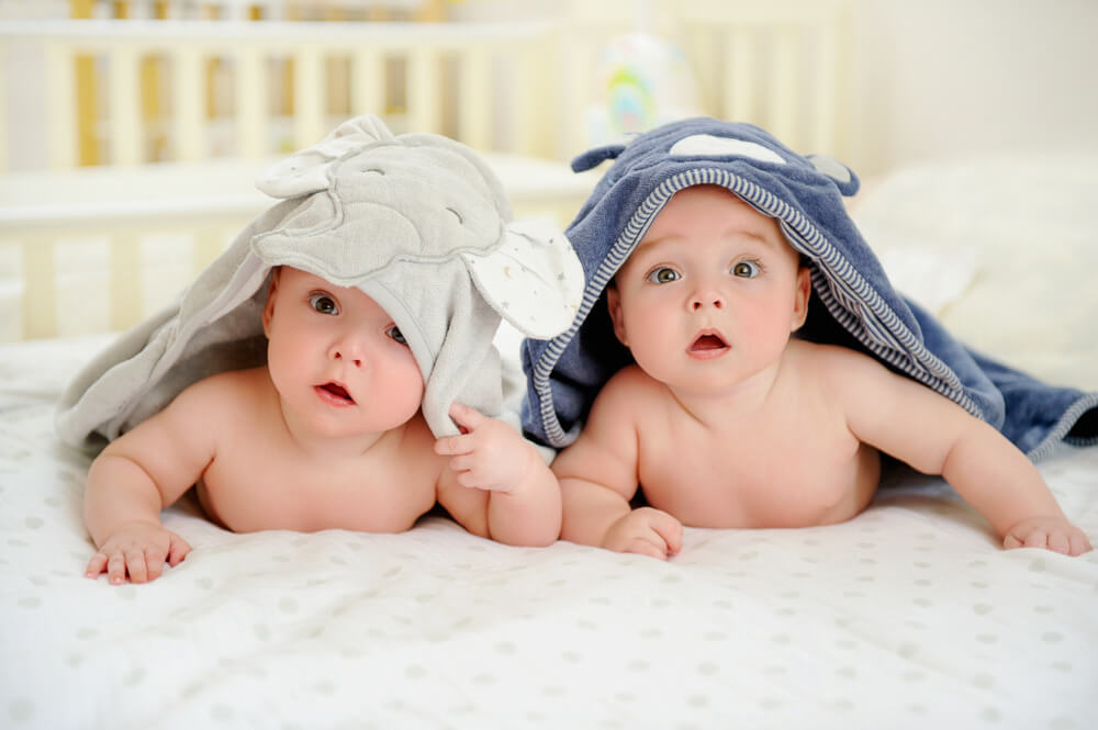 Adorable Five Months Old Baby Boy Twins in Character Towels After Taking a Bath or Shower, in Bed at Home.