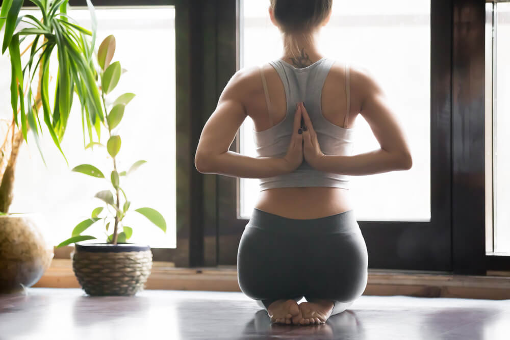 Young Woman Practicing Yoga With Namaste Behind the Back, Sitting in Seiza Exercise, Vajrasana Pose