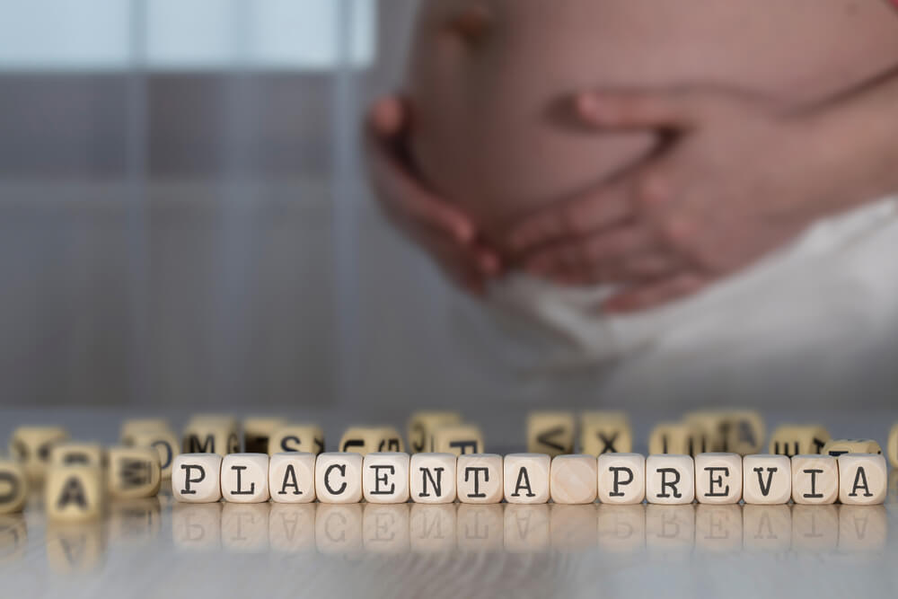 Words Placenta Previa Composed of Wooden Letters. Pregnant Woman in the Background