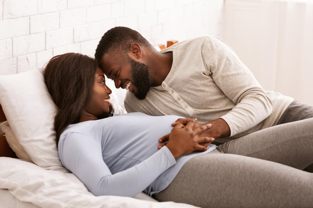 Pregnant Black Couple in Love Cuddling in Bed at Home