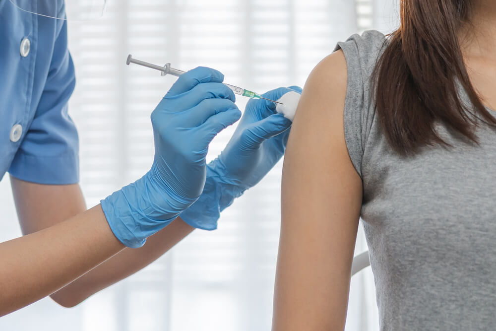 Hand of Young Woman Nurse,Doctor Giving Syringe Vaccine, Inject Shot to Asian Arm’s Patient