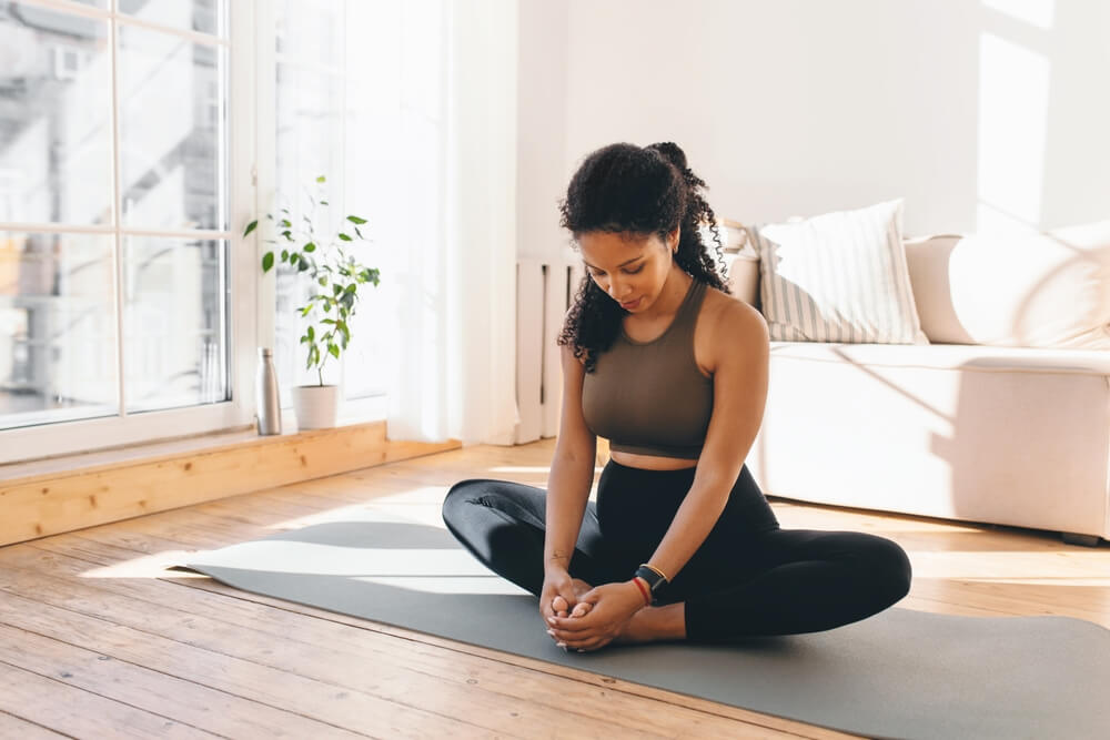 Active Pregnant Woman Practicing Yoga, Sitting in Butterfly or Konasana Pose, Stretching Muscles on Mat