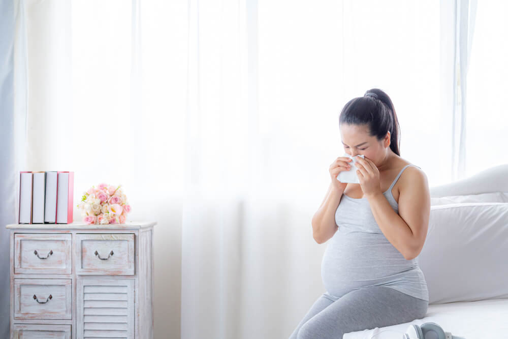 A Pregnant Women Blowing Runny Nose With Tissue Because She Has Flu