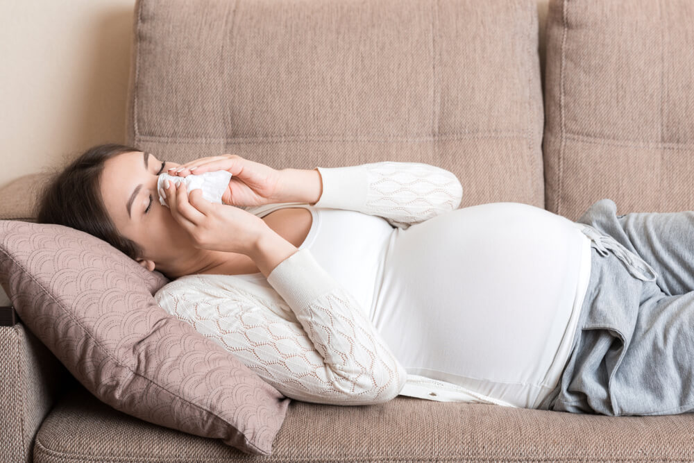 Sick Pregnant Woman Blowing Nose Into Tissue at Home Healthy Millennial Healthcare Concept