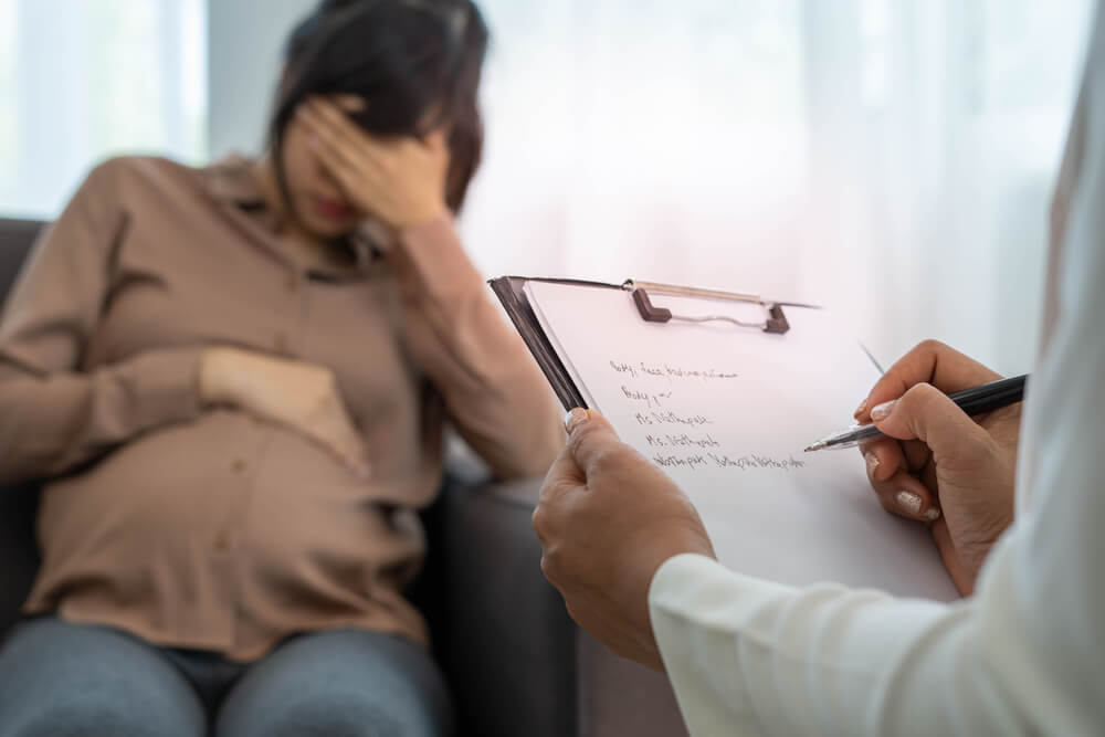 A general practitioner or psychiatrist or obstetrician discusses symptoms of depression during pregnancy among pregnant women
