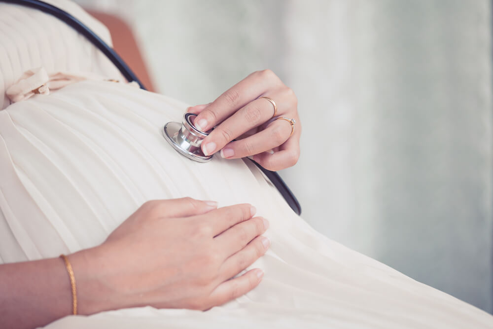 Pregnant Woman Using Stethoscope Examining on Her Baby in Her Belly
