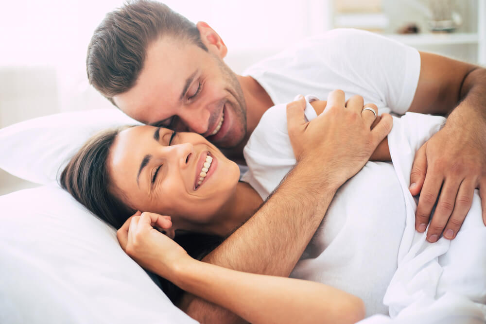 Happy Cute Young Beautiful Couple in Love Hugging Each Other in Bed
