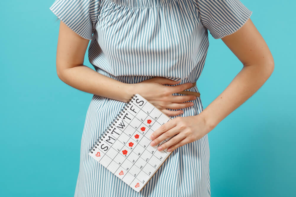 Woman in Blue Dress Holding Periods Calendar for Checking Menstruation Days