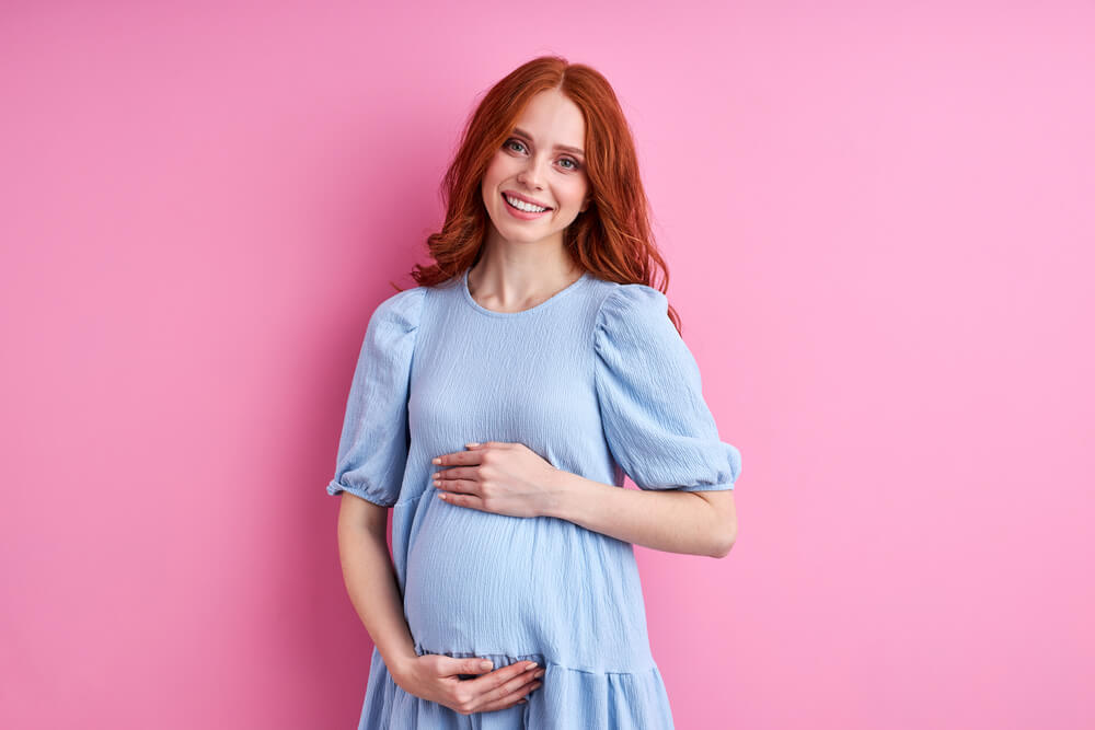 Pregnant Woman Posing at Camera Isolated on Pink Background