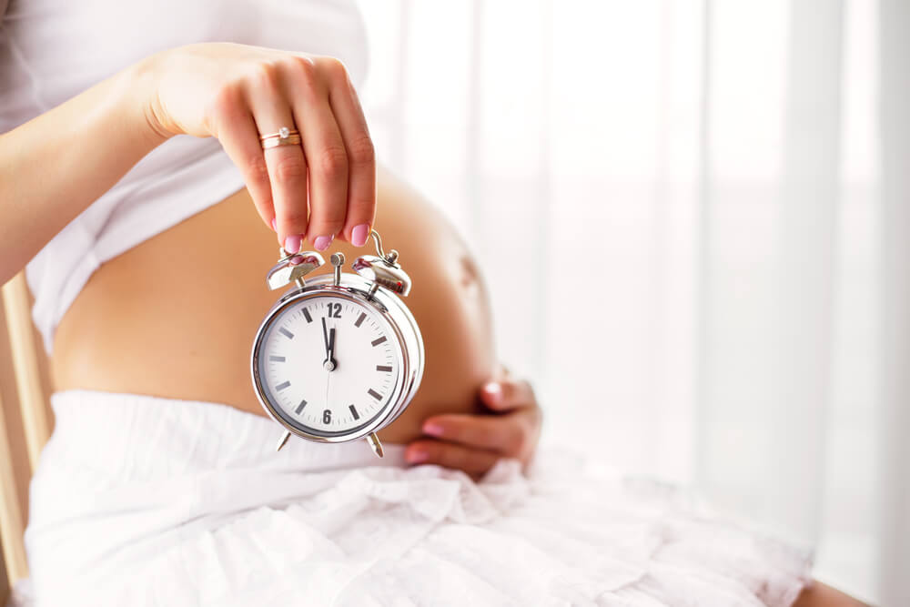 Pregnant Woman Holding Clock