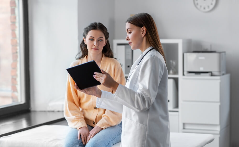 Gynecologist Talking With Young Female Patient During Medical Consultation in Modern Clinic.