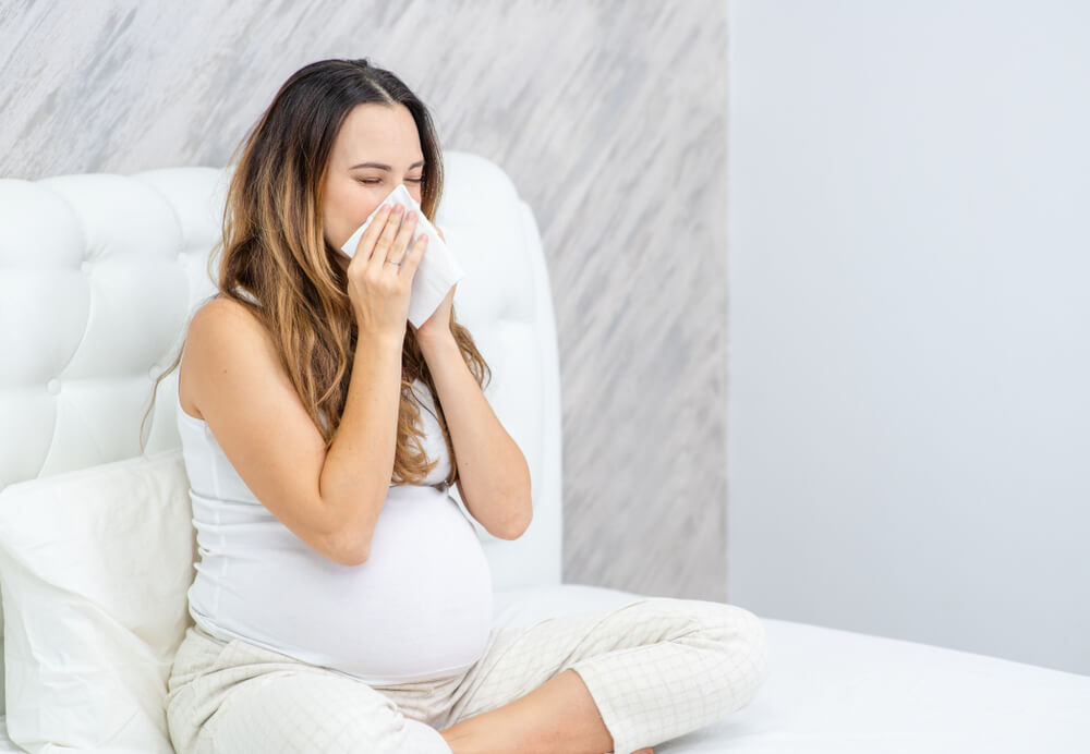 Pregnant Woman Blows Her Nose While Sitting on the Bed