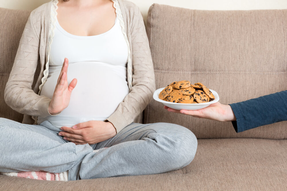 Pregnant Woman Sitting on the Sofa Refuses to Eat Cookies 