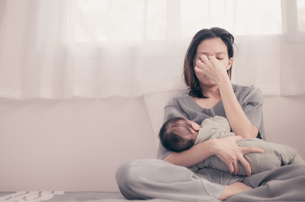 Tired Mother Suffering From Experiencing Postnatal Depression.