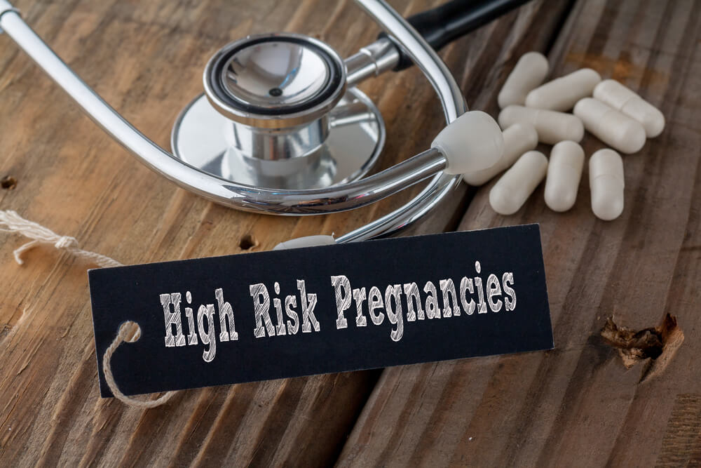 High Risk Pregnancies Written on Label Tag With Pills and Stethoscope on Wood Background