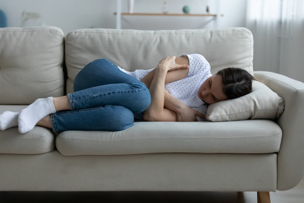 Depressed Young Woman Lying on Couch on Living Room Feeling Distressed