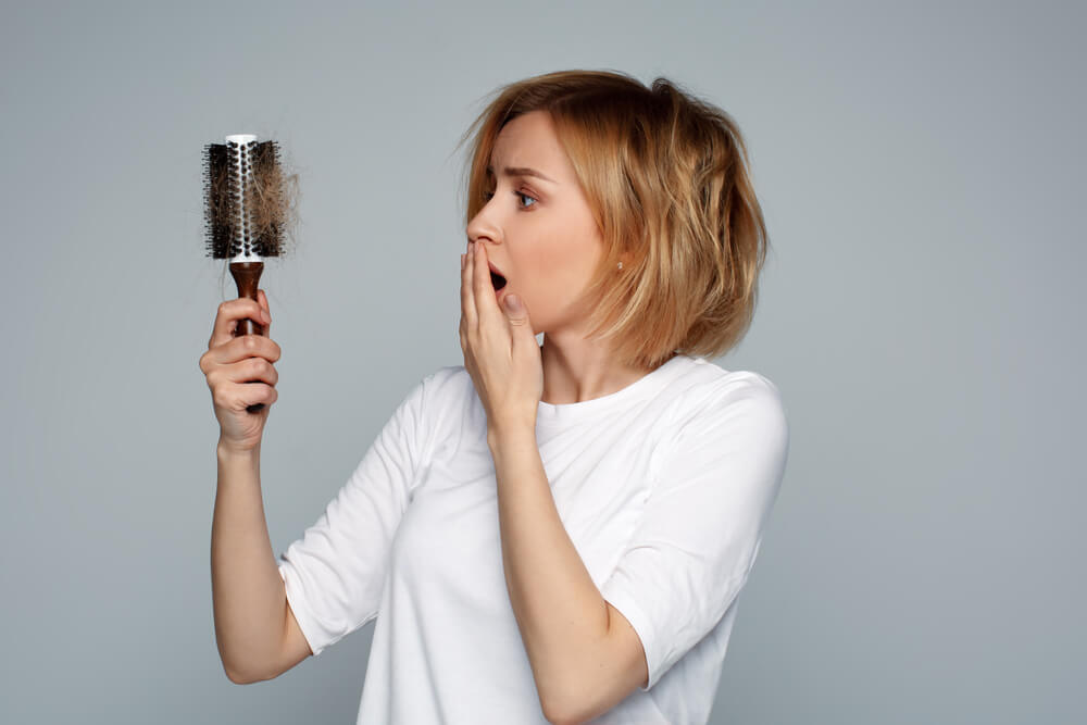 Blonde Young Worried Woman Holding Hairbrush With Unexpected Hair Loss Problem Alopecia Worried and in Fear Thinking of Solution