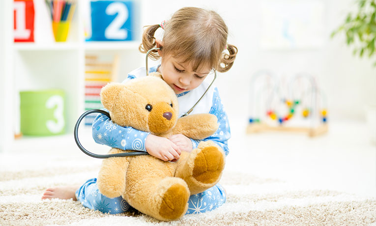 Little girl playing doctor with her Teddy bear