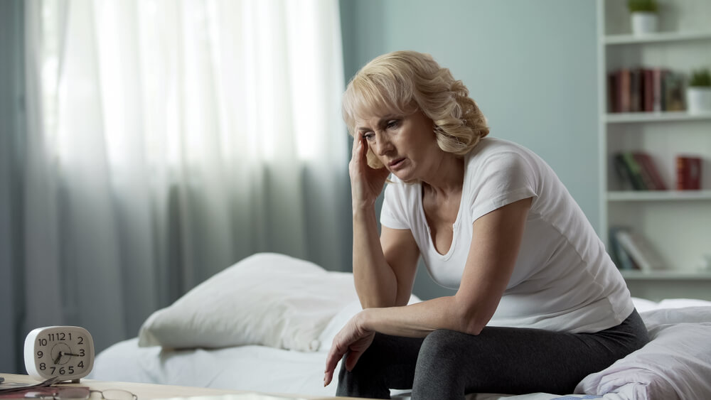Adult Female Sitting on the Bed and Suffering From Migraine