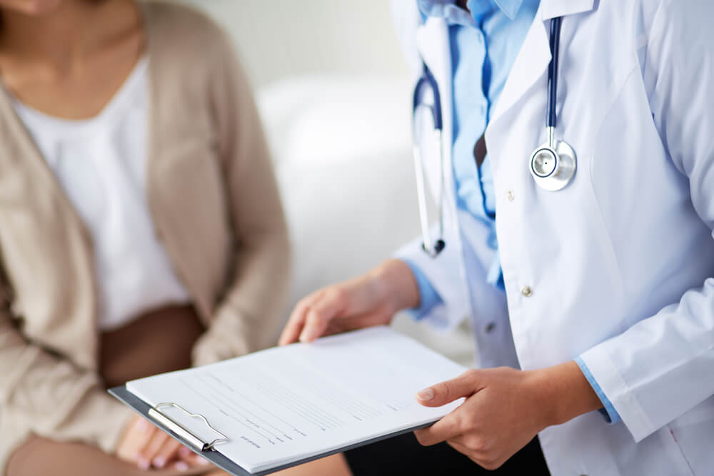 Female Doctor Holding Application Form While Consulting Patient