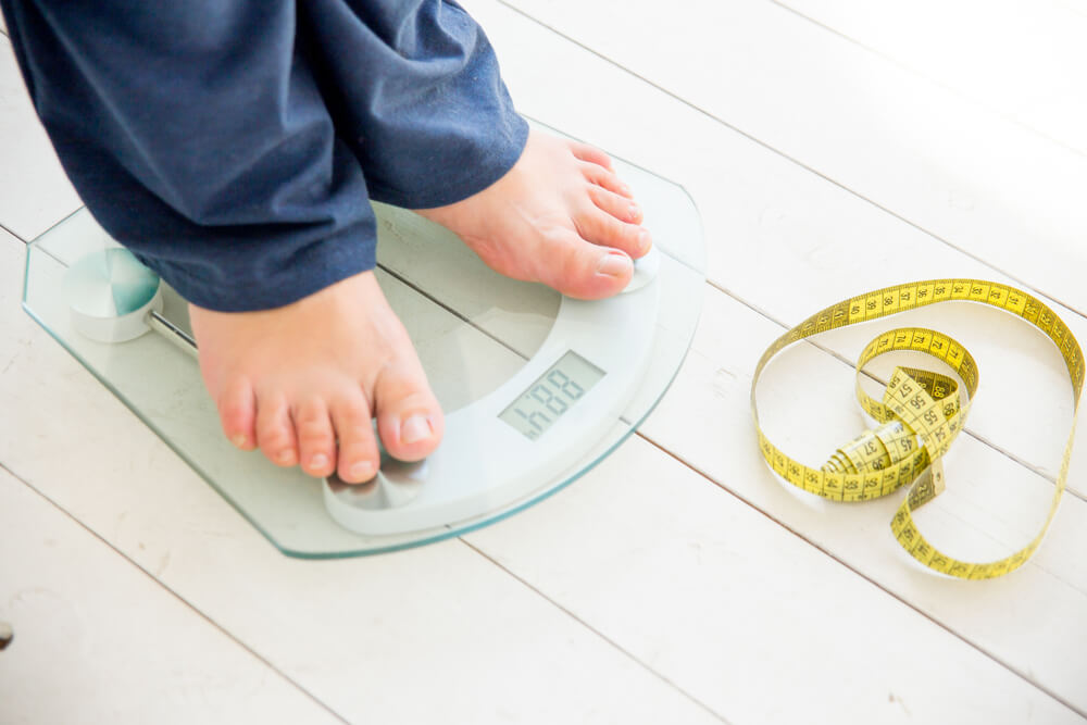 Pregnant Woman Standing on Scales to Control Weight Gain