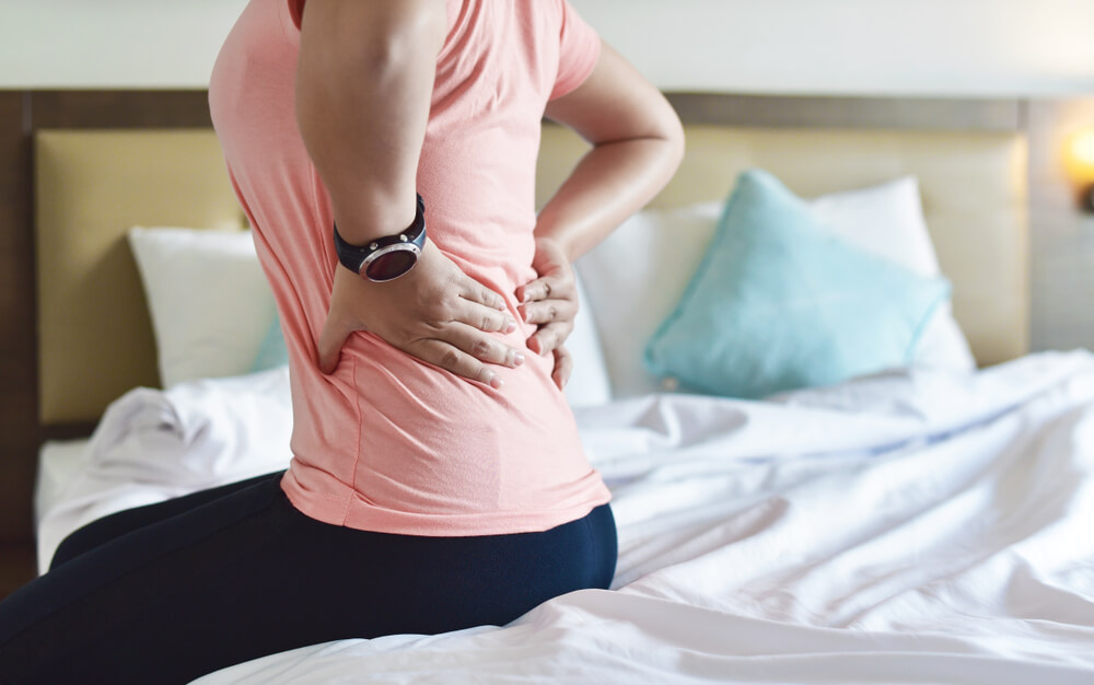 Back Pain, Close Up of Young Woman Hand Holding Back During Sitting in the Bed Room