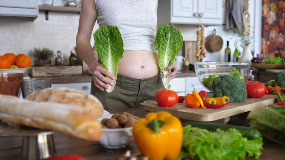 Close-Up Of Belly Of Pregnant Woman With Green Salad