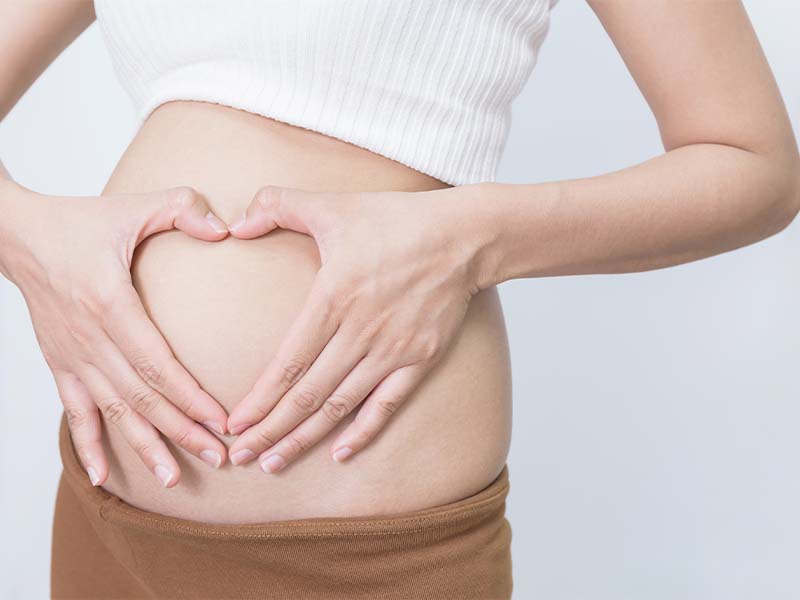 woman holding a heart over her pregnant belly