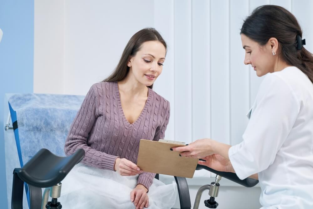 Concentrated Woman Reading Document in Presence of Her Doctor