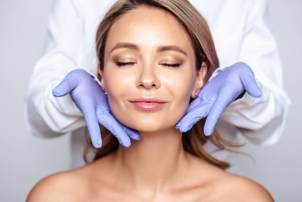 Close Up Portrait of Young Blonde Woman With Cosmetologyst Hands in a Gloves