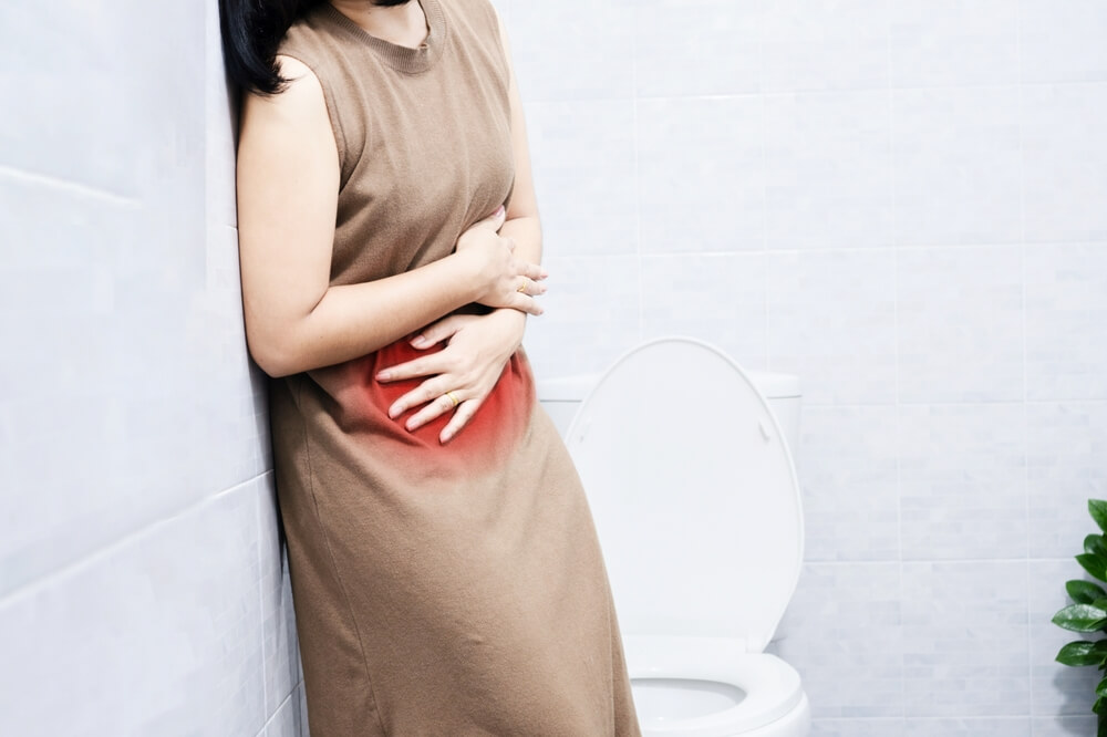 PMS concept with A Woman suffering from Menstrual Pain Holding Her Stomach in a Restroom
