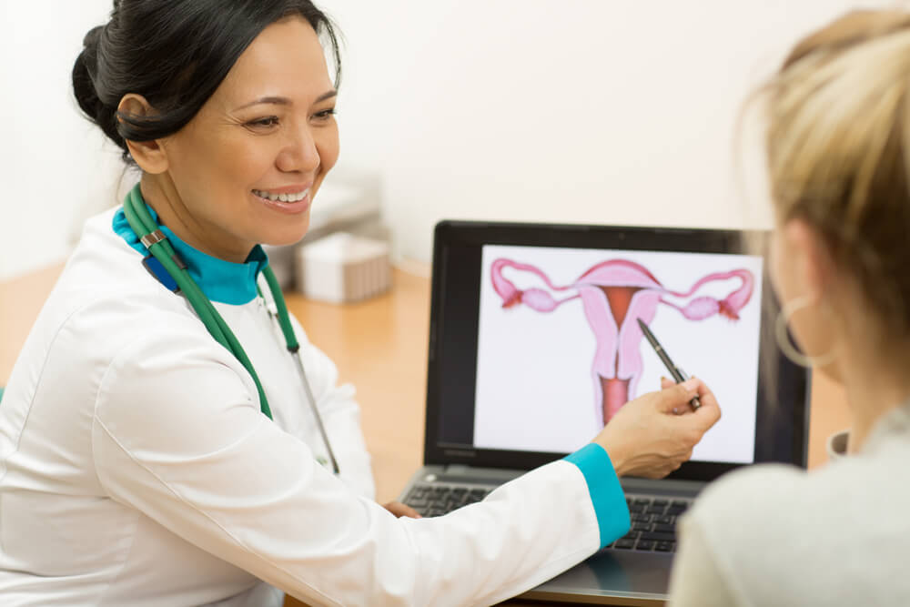 Mature female doctor showing her female patient picture of a uterus on the laptop