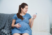  nærbillede af gravid kvinde, der læser vitaminpiller prænatal medicin.