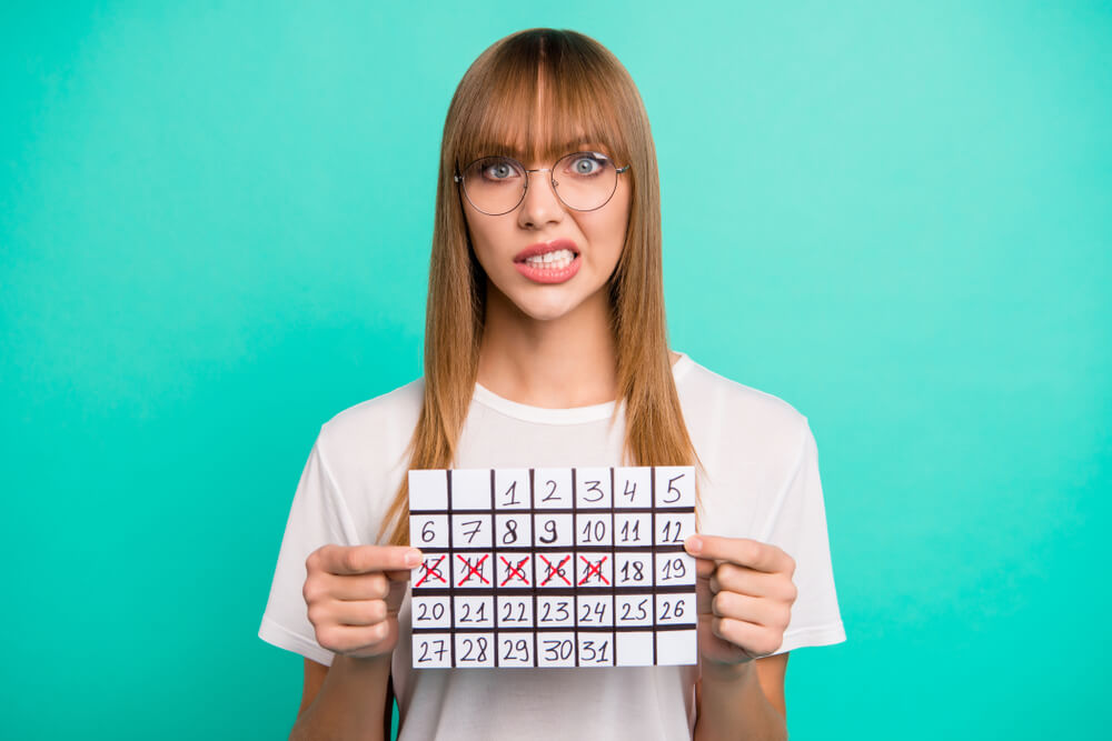 Woman Holding a Menstrual Calendar With Crossed off Dates