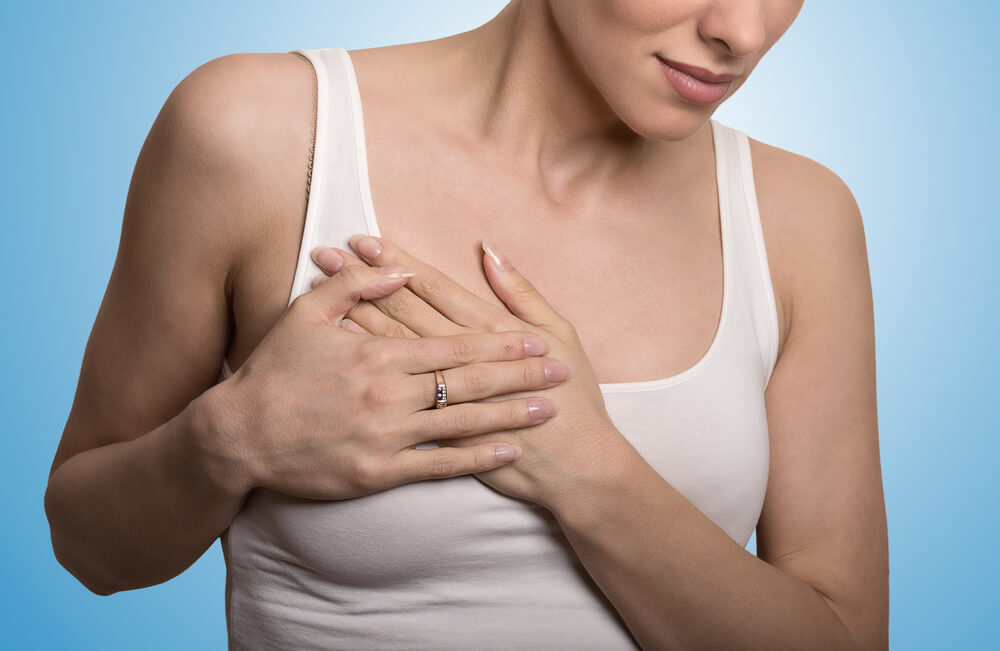 Closeup Cropped Portrait Young Woman With Breast Pain Touching Chest Colored Isolated on Blue Background