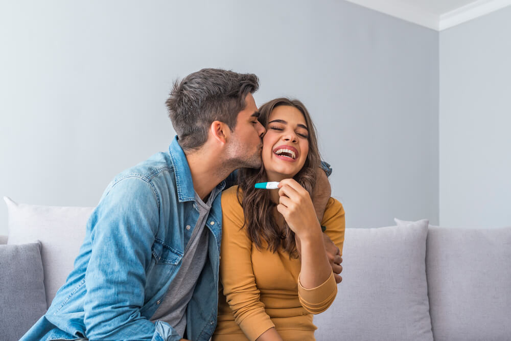 Joyful Couple Finding Out Results of a Pregnancy Test at Home. Happy Couple Looking at Pregnancy Test