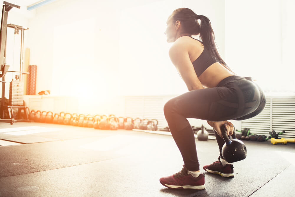 Athletic Woman Exercising With Kettle Bell While Being in Squat Position.